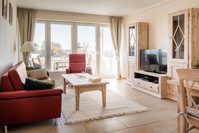 Helles Wohnzimmer mit Ledercouch und Blick zum Balkon mit Meerblick