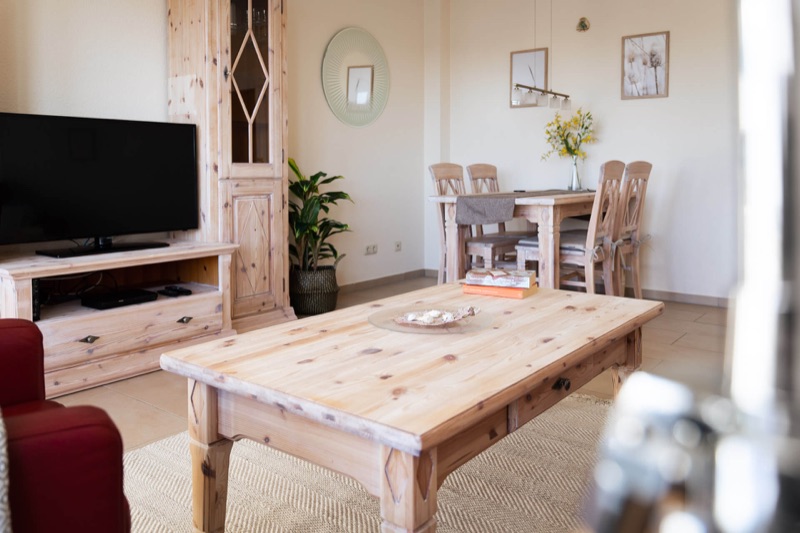 Wohnzimmer mit Smart-TV und Essecke für vier Personen