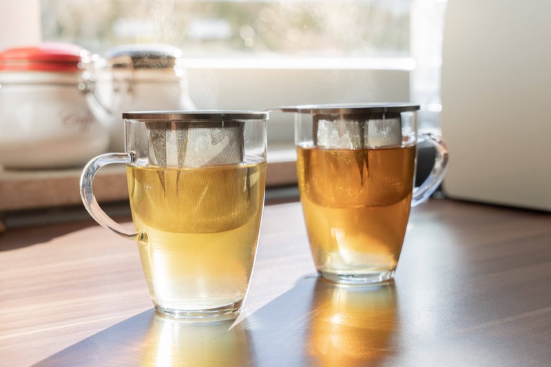 Zwei dampfende Teetassen am Küchenfenster